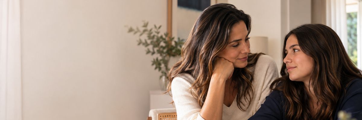 Mãe e filha conversando à mesa, em ambiente acolhedor